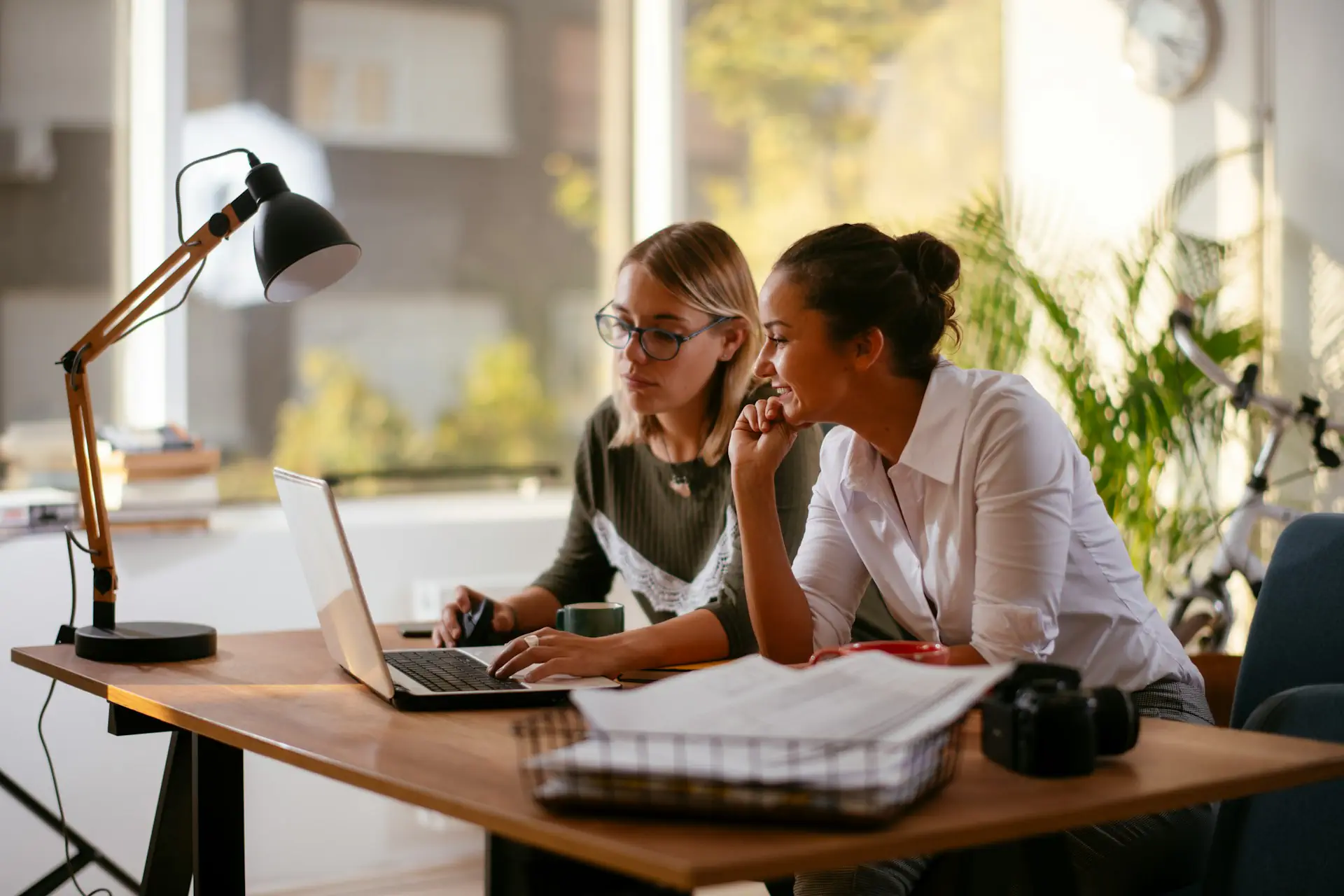 Two women collaborating at a desk with laptop.