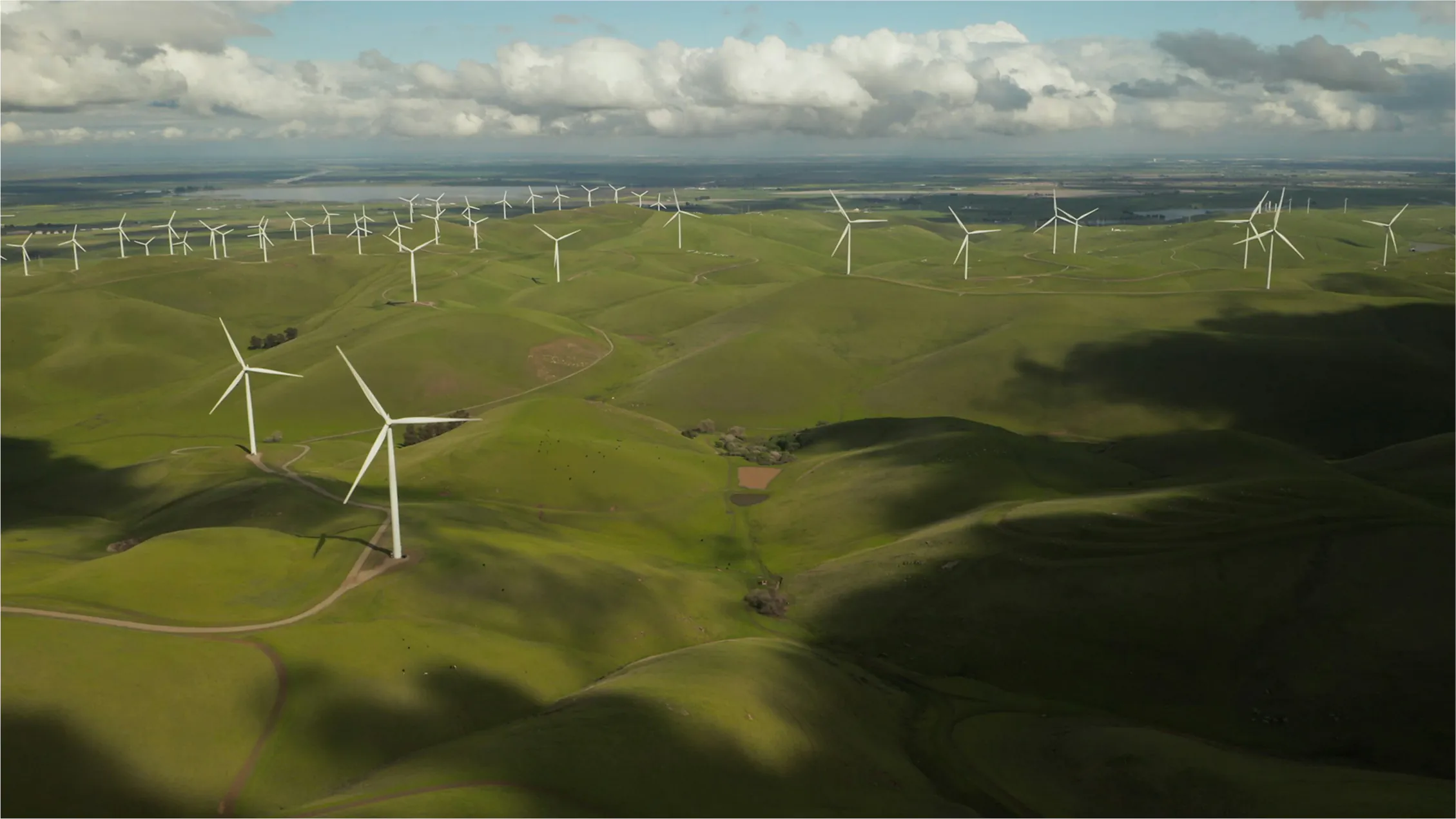 Wind turbines on green rolling hills landscape.
