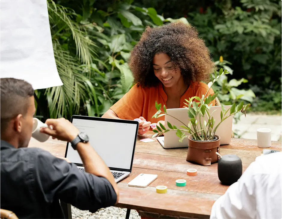 People working on laptops in outdoor setting.
